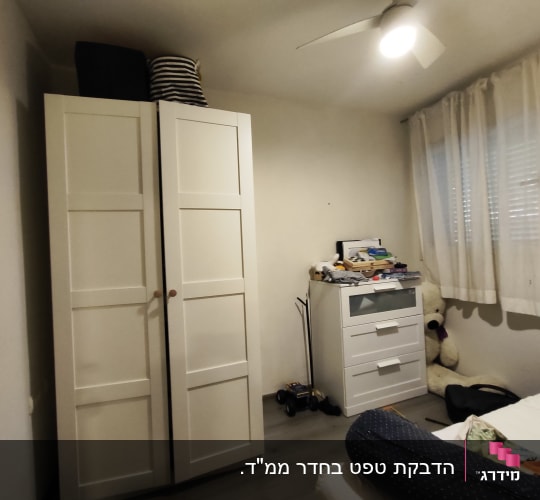 חדר שינה עם ארון בגדים לבן ומאוורר תקרה